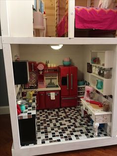 a dollhouse kitchen with red appliances and black and white checkered flooring is shown