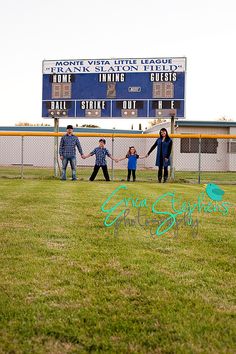 a group of people holding hands in front of a scoreboard at a baseball field