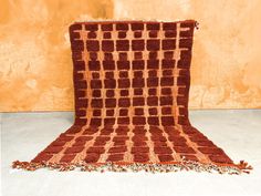 an orange and brown blanket sitting on top of a white floor next to a wall