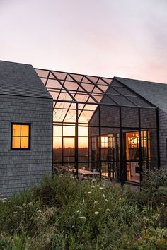 two buildings with glass windows are shown at sunset