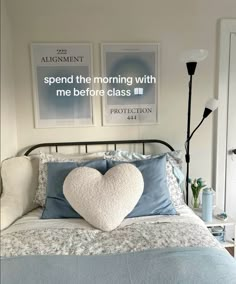 a heart shaped pillow on top of a bed in a room with two pictures above it