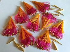 a bunch of pink and orange tassels with gold spikes on them sitting on a white surface