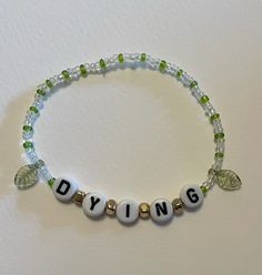 a beaded bracelet with the word dying written in white letters and green crystal beads