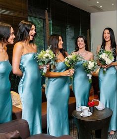 a group of women standing next to each other holding bouquets in their hands and laughing