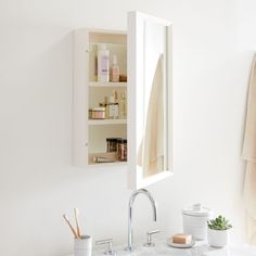 a white bathroom sink sitting under a mirror next to a shelf with bottles on it