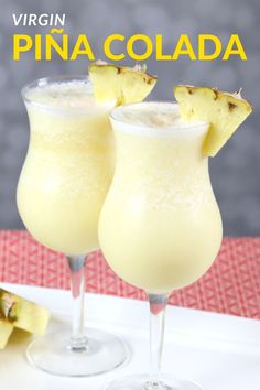 two glasses filled with pineapple drink sitting on top of a table