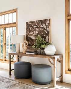 a table with two stools and a painting on the wall behind it in a living room