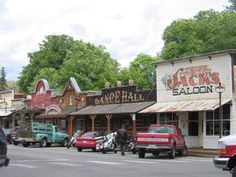 cars are parked on the street in front of businesses