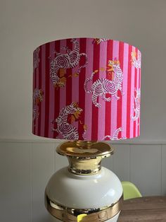 a pink and white lamp sitting on top of a wooden table