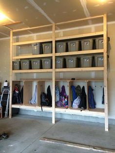 a garage filled with lots of buckets and bins next to a ladder on the wall