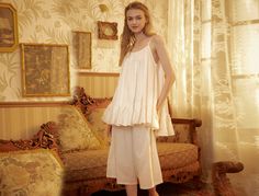 This listing is for the top only. Immerse yourself in the luxurious embrace of 100% cotton with this Victorian-inspired women's nightgown. Revel in the soft, cloud-like comfort and feel stunning in its roomy and super-voluminous design. The well-constructed garment features clean lines and elegant ruffles, creating a breathable and lovely experience. Embrace the cooling comfort of the scoop neck design and enjoy the full and lovely, yet modest, outfit that allows unrestricted movement. This nightgown, reminiscent of the royal court style of the Victorian Edwardian era, transcends being just a garment; it's the essence of dreams. Washed in the highest quality cotton, it remains cool and feminine, providing a regal experience that makes you feel like a Victorian Princess. Its authenticity sh Medieval Sleepwear, Nightgown Cotton, Sleeveless Nightgown, Modest Outfit, Plus Size Pajamas, Maternity Gowns, Women's Nightgowns, Nightgowns For Women, White Lingerie