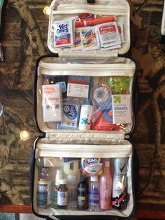 an open suitcase filled with personal care items on top of a wooden table next to a wall