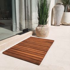 a potted plant sitting on top of a wooden mat next to a glass door