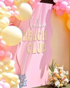 a pink and white backdrop with balloons, flowers and a sign that says collin's beach club