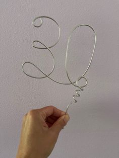 a hand holding a metal wire type object with the word love spelled in cursive writing