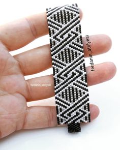 a hand holding a black and white beaded bracelet