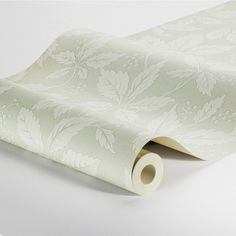 a white wallpaper with leaves and flowers on it's side, next to a roll of tape