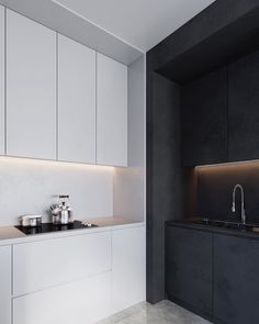 a kitchen with white cabinets and black countertops is lit by recessed lighting above the sink