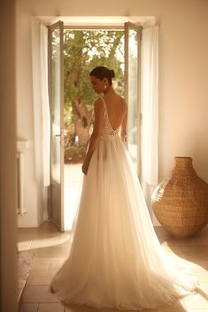 a woman in a wedding dress looking out the window