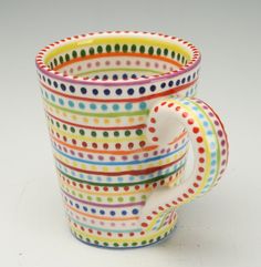 a stack of multicolored coffee cups sitting on top of each other in front of a white background