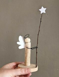 a hand holding a small wooden angel with a star on it's back and an arrow in the other hand