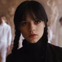 a woman with black hair and braids looks at the camera while standing in an empty room