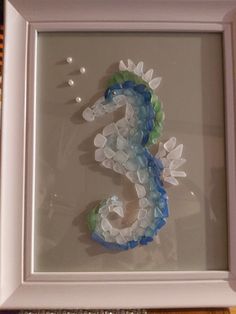 a seahorse made out of glass in a white frame