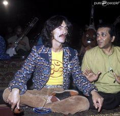 two men sitting on the floor with guitars in the background and one man holding his hands out