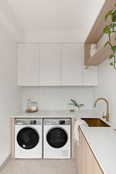 a washer and dryer in a small room with white cabinets on the wall