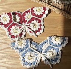 two crocheted butterflies sitting on top of a wooden table