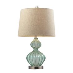 a green glass lamp with a beige shade on the base and a light brown linen lampshade