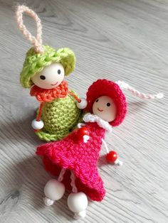 two small dolls sitting on top of a wooden table