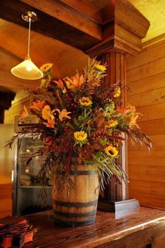 a vase filled with flowers sitting on top of a wooden table next to a fireplace