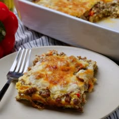 a white plate topped with lasagna next to a casserole dish