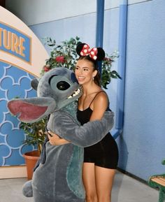 a woman hugging a stuffed animal in front of a sign