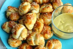 a blue plate topped with pastries next to a bowl of mustard and dipping sauce