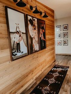 three framed pictures hang on the wall above a rug in a living room with wood paneling