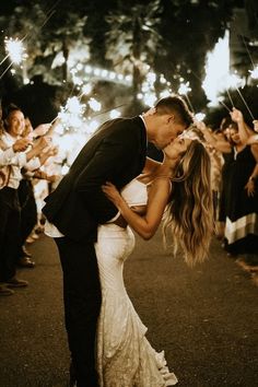 a newly married couple kissing in front of sparklers