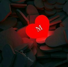 a red heart with the letter m on it surrounded by hearts