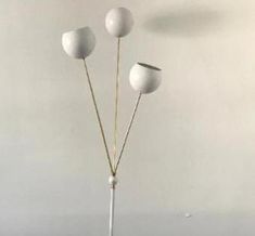 three white vases sitting on top of a wooden table next to each other in front of a wall