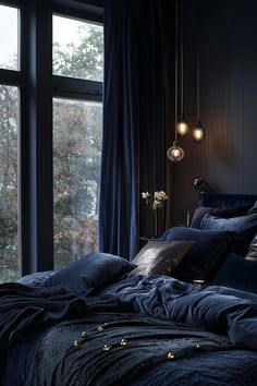 a bed with blue sheets and pillows in front of a large window