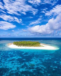 an island in the middle of the ocean with blue water and white sand on it