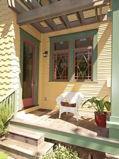 a porch with a chair and potted plant on the front steps next to it