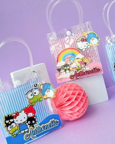 three bags with cartoon characters on them are sitting next to a tissue ball and paper fan