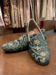 a pair of blue slippers sitting on top of a wooden table next to clothes