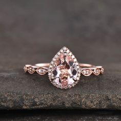 an oval shaped morganite and diamond engagement ring on top of a rock with diamonds around the band