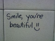 a sign that says smile, you're beautiful on the side of a toilet