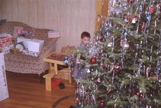 a young boy sitting in front of a christmas tree