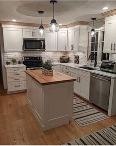 a kitchen with white cabinets and wooden counter tops, an island in between the stove and refrigerator