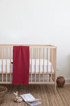 a baby crib with a red blanket next to it